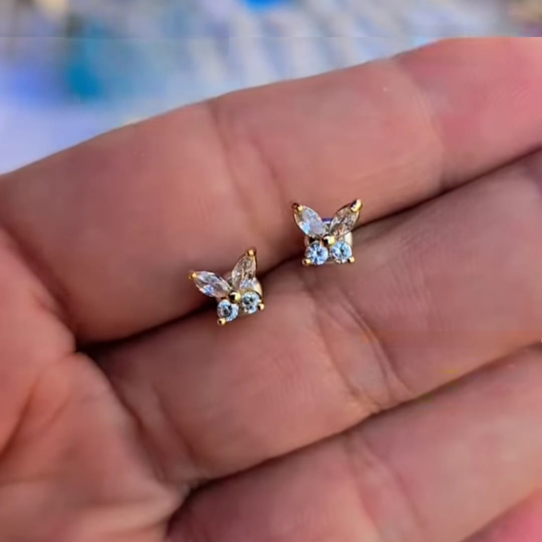 Aretes de botón mariposa en baño oro con piedras en tono cristal