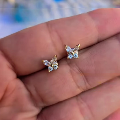 Aretes de botón mariposa en baño oro con piedras en tono cristal